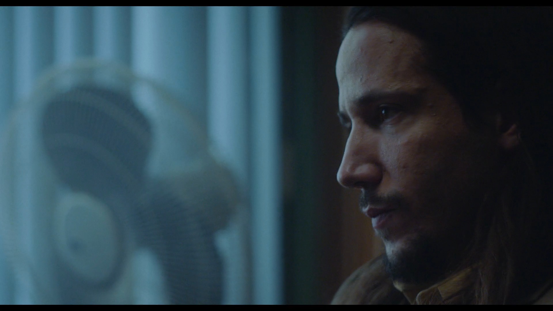 Wiggle Room — the agent broods in profile beside his desk fan